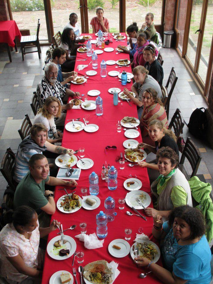 The MSU Denver Office of International Studies holding a dinner with a group of people at a long table in Ethiopia